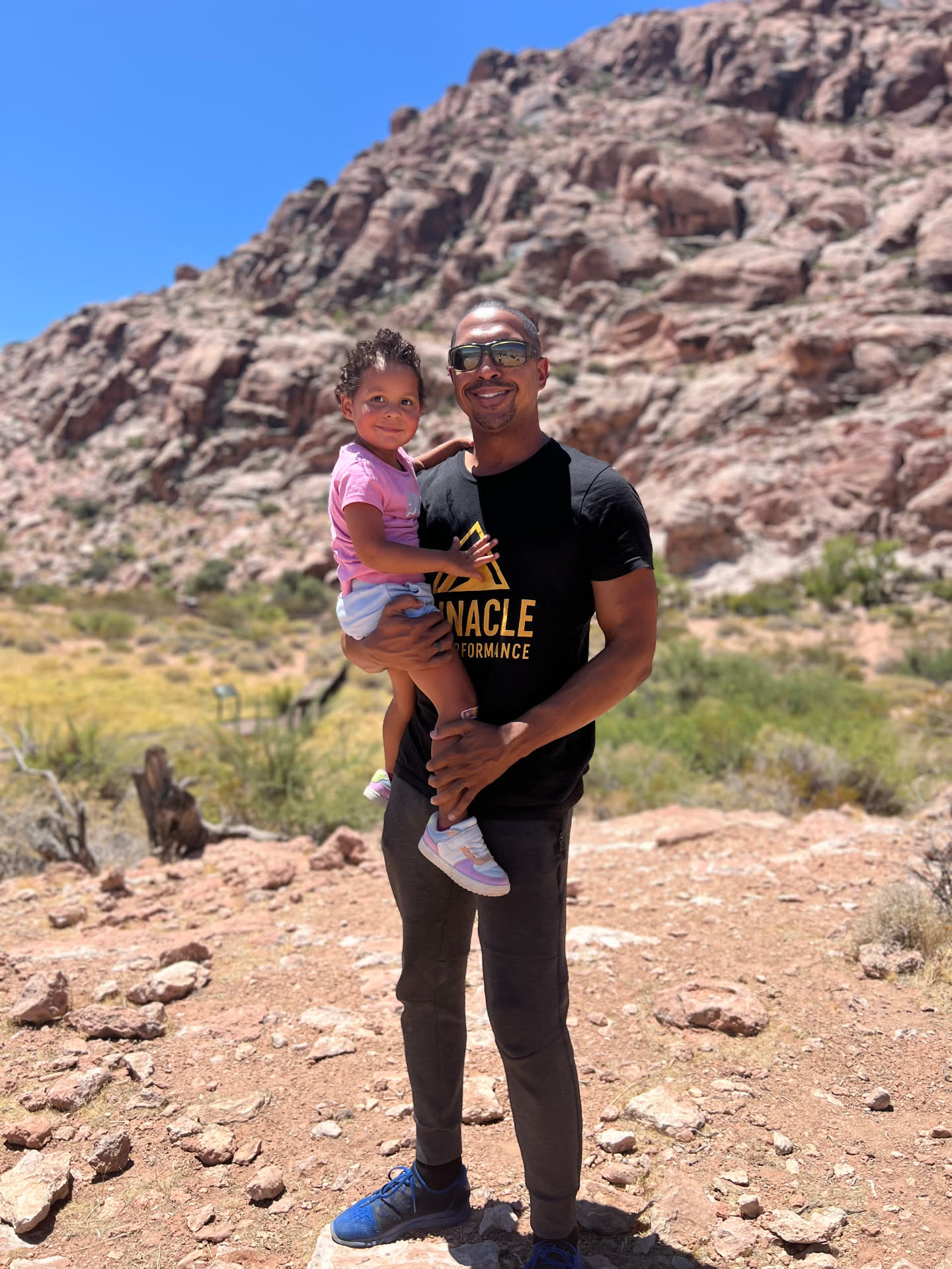 John Hall holding a young child on a rocky mountain trail